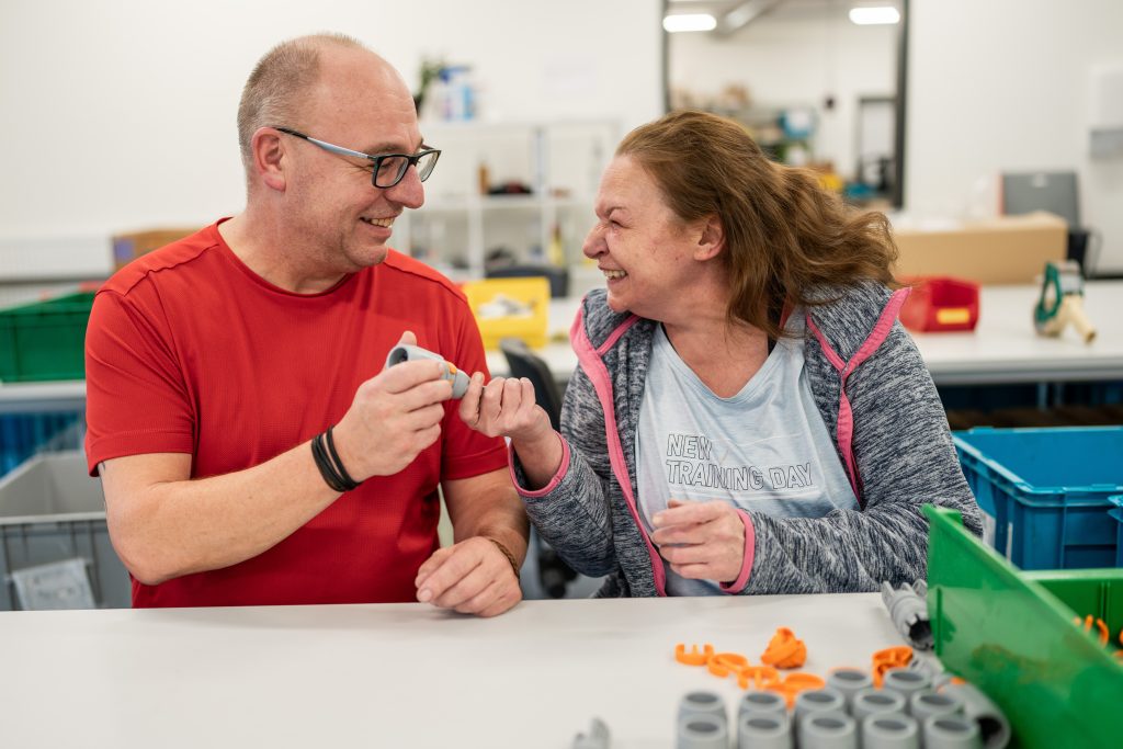 Mann und Frau sind glücklich und lachen während der gemeinsamen Arbeit in der Werkstatt